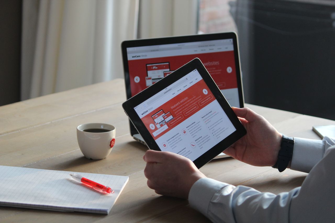 Crafting Captivating Headlines: Your awesome post title goes here Business professional using a tablet and laptop with a hot drink, focusing on digital content review.